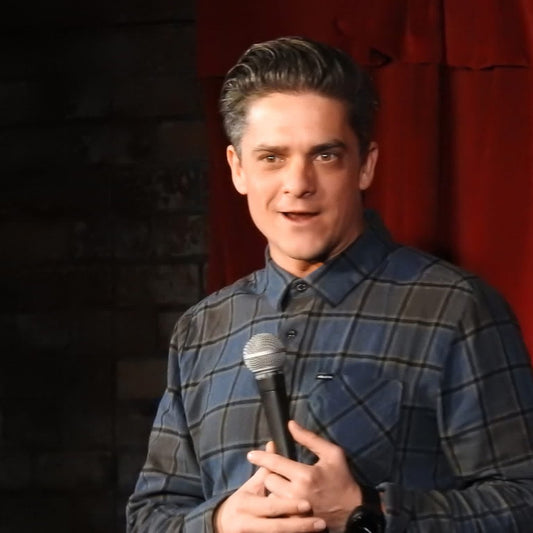 Man holding a microphone in front of a red curtain